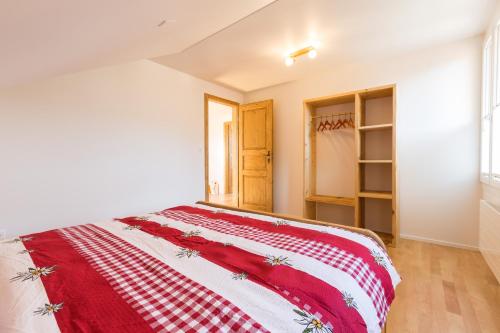 a bedroom with a red and white blanket on a bed at Pilatus Apartments in Alpnach
