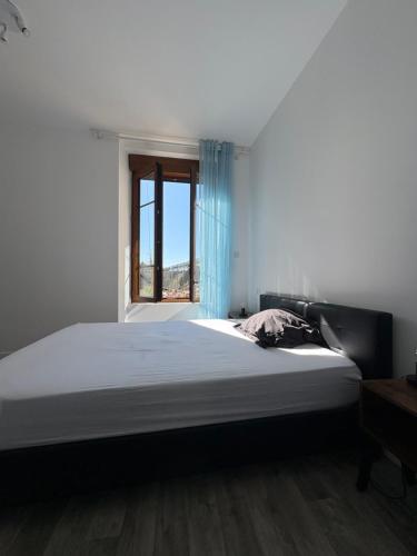 a bedroom with a large bed with a window at Chambre avec salle de bain privé in Neuvic