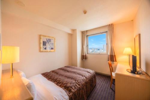 a hotel room with a bed and a window at Hirosaki Plaza Hotel in Hirosaki