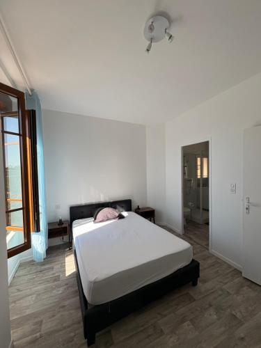 a white bedroom with a bed in a room at Chambre avec salle de bain privé in Neuvic