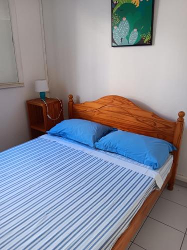 a bedroom with a wooden bed with blue pillows at L'îlot vacances in Saint-Pierre
