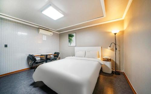 a bedroom with a white bed and a table and chair at Dapsimni Hotel Grim in Seoul