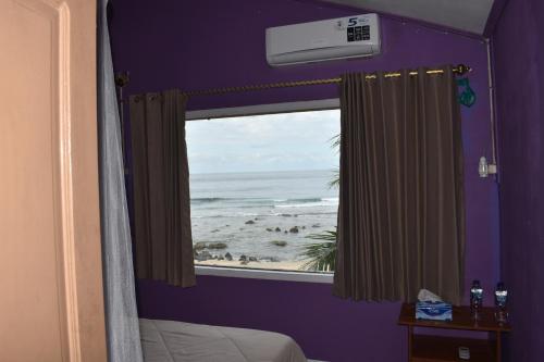 a bedroom with a window with a view of the beach at Puri Ma'u Beach & Bungalows in Boba