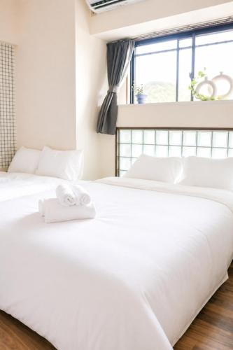 two white beds in a bedroom with a window at サンヒルズマンション in Tosu