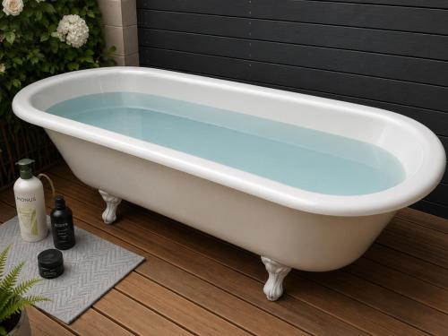 a white bath tub sitting on a wooden floor at Bach By The Beach in Mount Maunganui