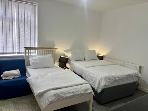 a bedroom with two beds and a blue couch at HomesRentals Studio in Dudley