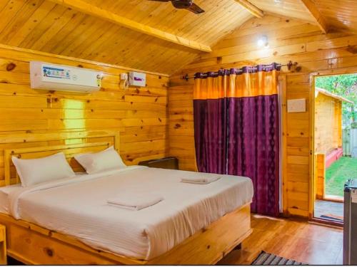 a bedroom with a bed in a wooden cabin at Village Sunset Paradise Beach Resort in Morjim