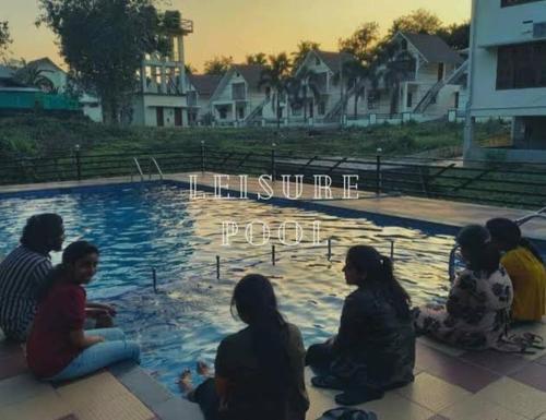 a group of people sitting around a swimming pool at Villas NEST Athirappilly in Athirappilly