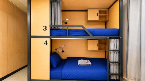 a room with three bunk beds with blue sheets at Destiny Hostel Pattaya in Jomtien Beach