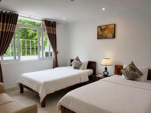 a hotel room with two beds and a window at KHÁCH SẠN ROMO in Quảng Ngãi