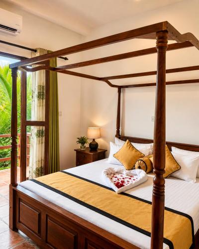 a bedroom with a canopy bed and a window at River Bay Hotel in Pillagoda
