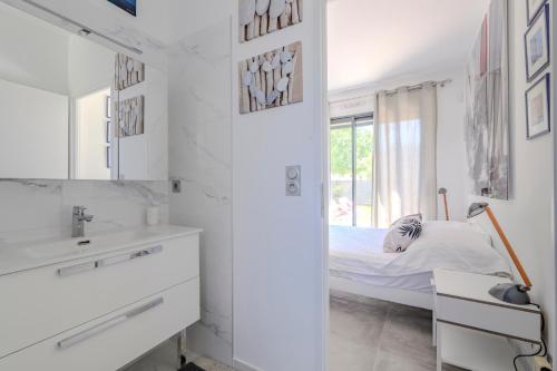 a white bedroom with a bed and a mirror at Villa Npda in Carpentras