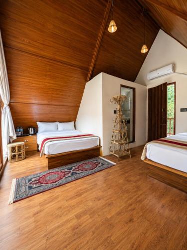 a bedroom with two beds and a wooden ceiling at Sukute River Hub Beach Resort in Dolālghāt