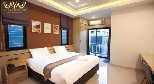 a bedroom with a large white bed with windows at Aiyara Riverine Hotel, Nakhon Phanom in Ban Nong Puk