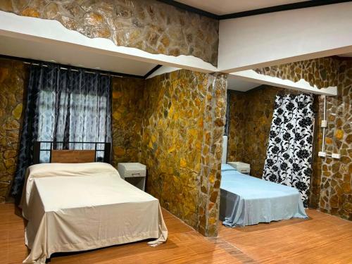 a bedroom with two beds and a stone wall at Churinga Eco Resort in Tigaon