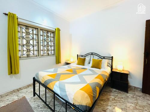 a bedroom with a bed and a window with yellow curtains at Aamra Ghar by evaddo stays in Mandrem