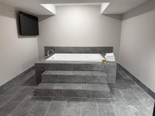 a bathroom with a bath tub and a television at Clarion Pointe Addison - Dallas North in Addison