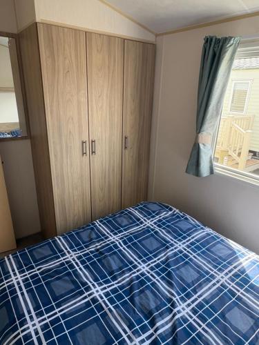 a bedroom with a bed with a blue plaid sheet at TSCaravan, Haven, Golden Sands in Mablethorpe