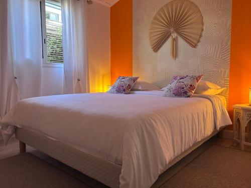 a bedroom with a white bed with an orange wall at Le djebel in Cilaos