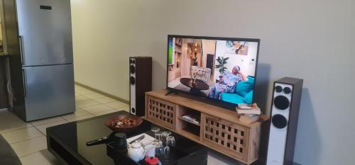a living room with a flat screen tv on a stand at Northview APARTMENTS SELF CATERING in Pretoria