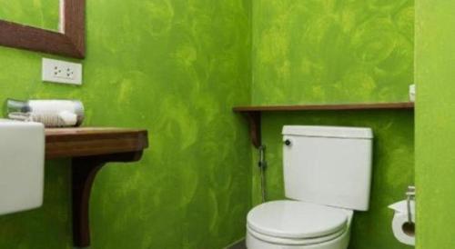a green bathroom with a toilet and a sink at Baan Supparod in Ko Samed