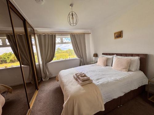 a bedroom with a bed with white sheets and windows at Hebridean Country House in Lochs