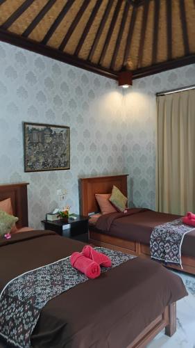 a bedroom with two beds with red towels on them at Dewa Bungalows, A Balinese House and Art Gallery in Ubud