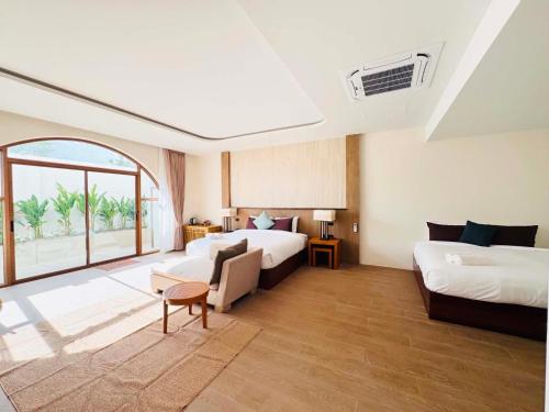 a hotel room with two beds and a couch at Merry Holmes Resort Hatyai in Ban Tha Sae