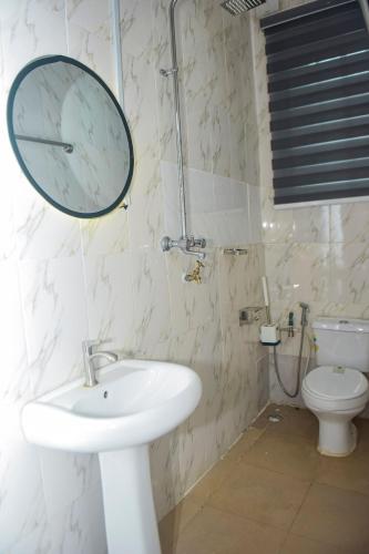 a bathroom with a sink and a mirror and a toilet at Living Space Service Apartment in Mama