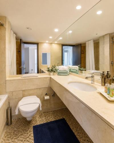 a bathroom with a toilet and a sink and a tub at מגדל אלמוג חיפה - דירות "בלו ביץ'" על הים in Haifa