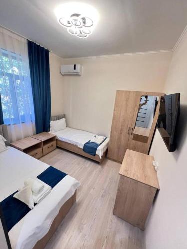 a room with two beds and a tv in it at Hotel City Land Tashkent in Yakkasaray