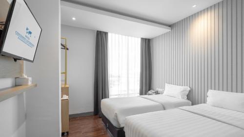 a hotel room with two beds and a flat screen tv at Continent CentrePoint Makassar in Pampang