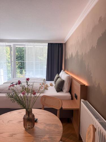 a room with a bed and a table with a vase of flowers at ALPURA Allgäu - Active Nature Retreat - HOTEL REOPENING in Bad Hindelang