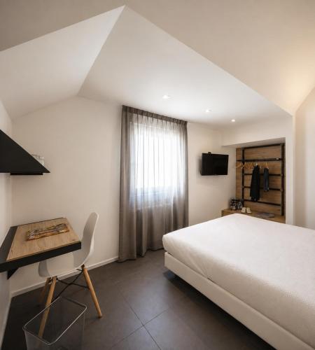 a bedroom with a white bed and a desk and a bed sidx sidx at Le Palme City Rooms & Breakfast in Trento