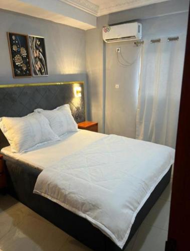a bedroom with a white bed with a air conditioner at Nandys lounge in Yaoundé