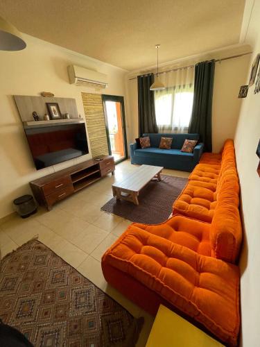 a living room with an orange couch and a blue couch at Furnished Chalet Apartment at La Hacienda Ras Sedr in Ras Sedr