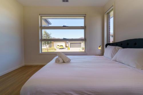 a bedroom with a large white bed with a window at Light-Filled Werribee Escape in Werribee