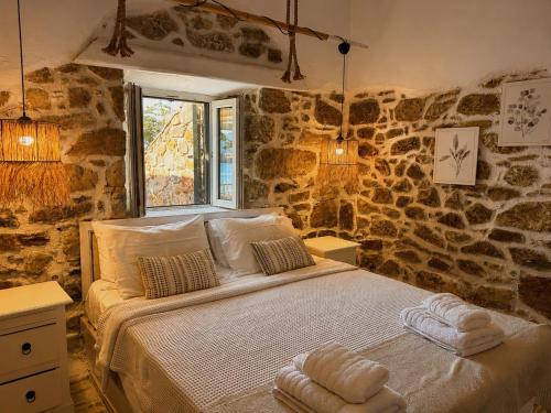 a bed in a room with a stone wall at Atlazia Suites in Alinda