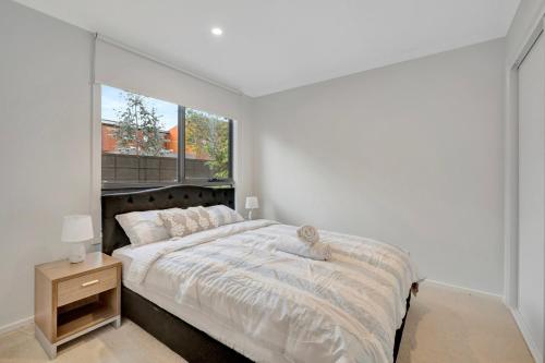 a white bedroom with a large bed and a window at Stylish 3-Bedroom Townhouse Near Shops & Parks in Point Cook