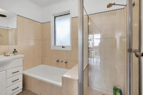 a bathroom with a shower with a tub and a sink at Hoppers Crossing Hideaway Giant Backyard in Tarneit