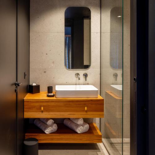 a bathroom with a sink and a glass shower at Wood Hôtel & Spa in Saint-Gilles-les-Bains