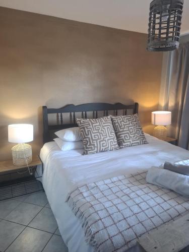 a bedroom with a bed with pillows and two lamps at Blouberg Beach Escape in Cape Town