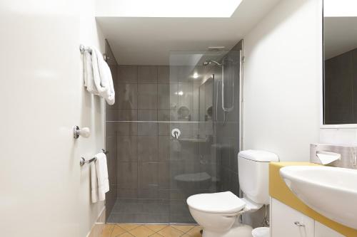 a bathroom with a shower and a toilet and a sink at West End Central Apartments in Brisbane