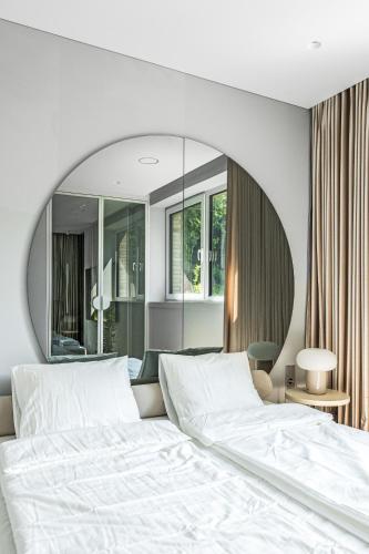 a bedroom with a large white bed with a round mirror at Refined luxury apartment surrounded by forest in Vilnius