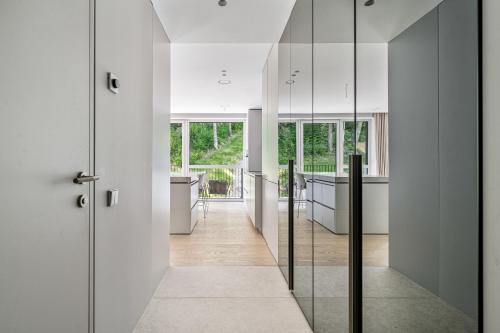 a hallway with white walls and glass doors at Refined luxury apartment surrounded by forest in Vilnius
