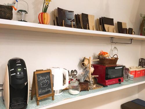 a shelf with a toaster and a microwave on it at Hiroshima Guesthouse HARU in Hiroshima