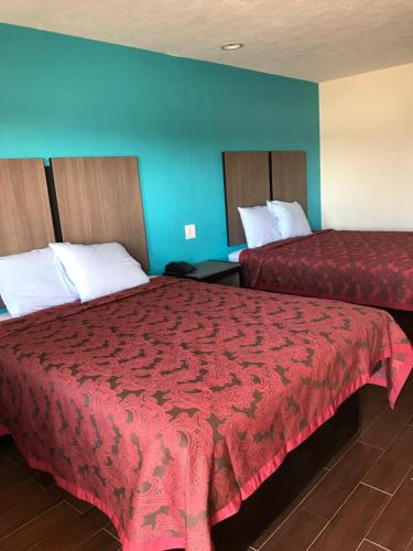 a hotel room with two beds with red sheets at Moonlight Inn & Suites in Houston