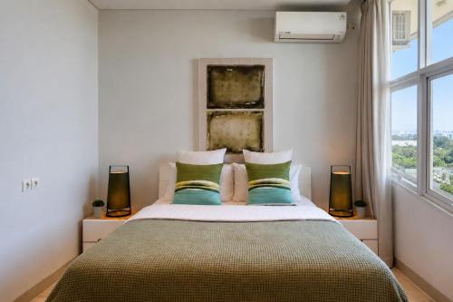 a bedroom with a bed with green pillows and a window at Dago Suite 3BR Luxury Apartment in Bandung