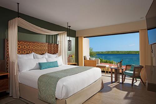 a bedroom with a bed and a view of the water at Secrets Papagayo All Inclusive - Adults Only in Papagayo, Guanacaste