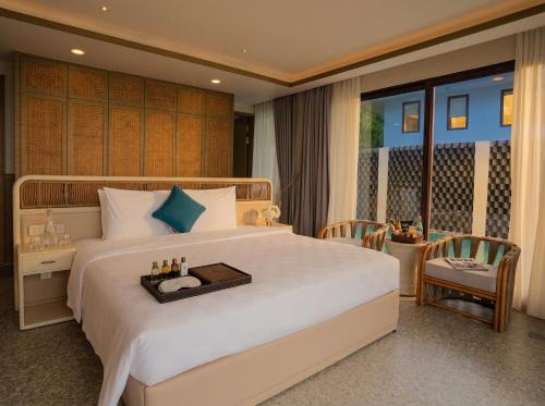 a bedroom with a large white bed with a table and chairs at Riahi Villas by Swiss-Belhotel, Nirup Island in Belakangpandang